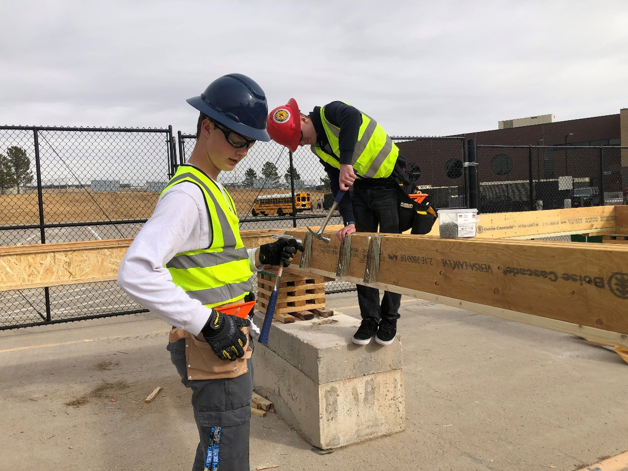 Two students work on constructing the floor of a new house.